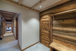 Ein Flur mit Holztür und einer Bank, der zu einem Schlafzimmer mit einem Bett führt.