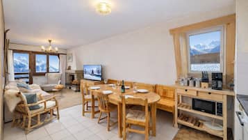 Una sala de estar acogedora con chimenea, un comedor con muebles de madera y una cocina con horno empotrado y ventana con vista a la montaña.