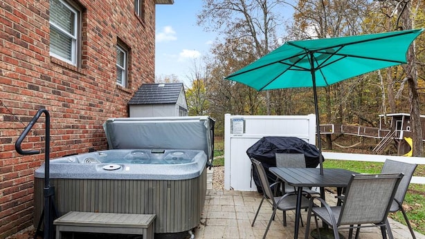 Ein Garten mit Whirlpool, Tisch und Stühlen im Freien sowie einem überdachten Grillbereich.