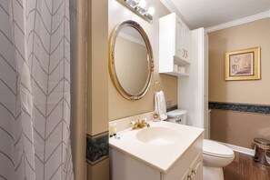 A bathroom with a vanity, a large mirror, a toilet, and a framed picture on the wall.
