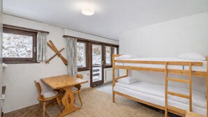 A room with bunk beds, a wooden table, chairs, and a window with curtains. - Apartment Mont-parrain C32 Bright & Central With Balcony (Riddes)