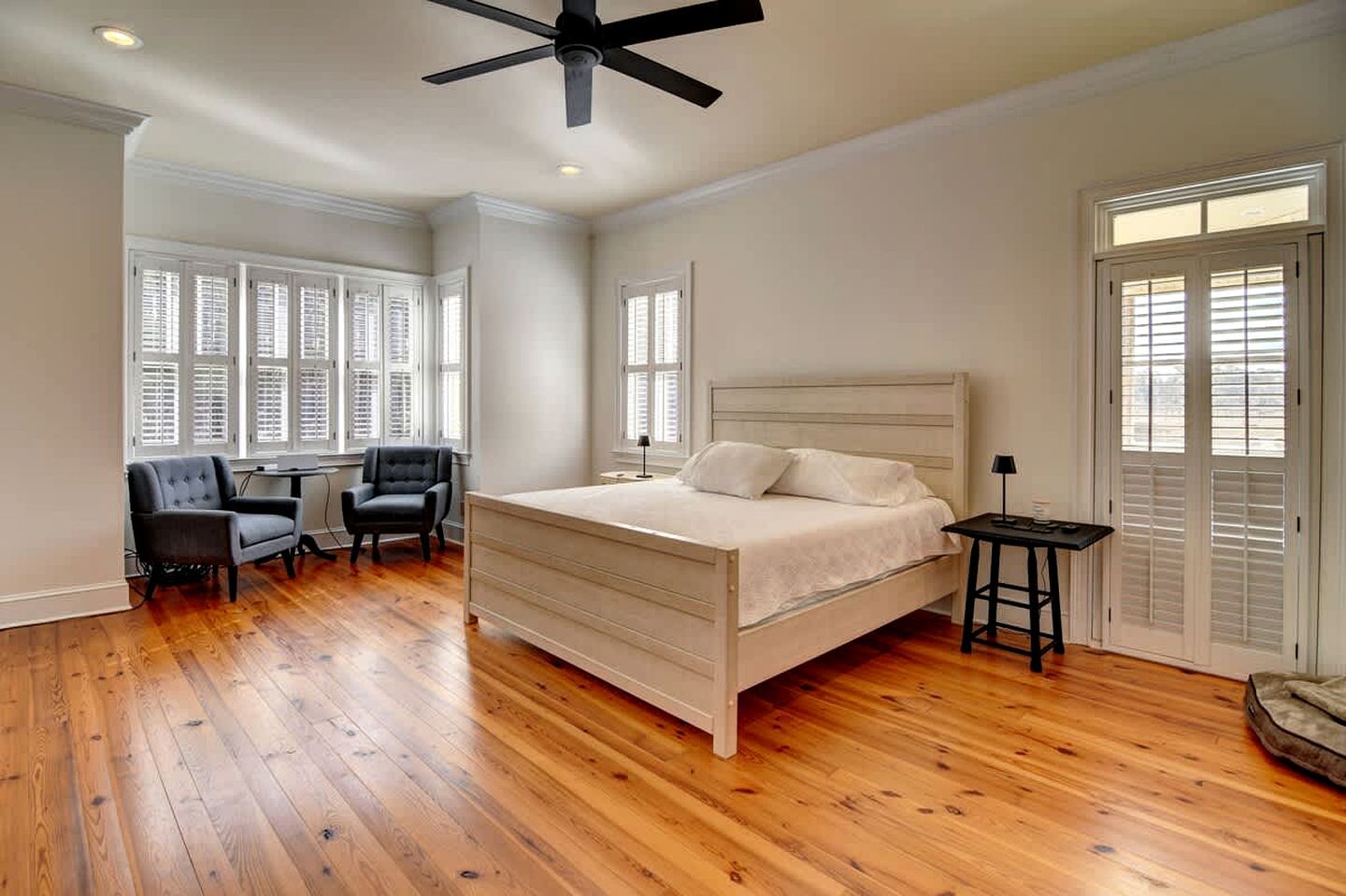 A bedroom with a bed, a chair, a desk, and a ceiling fan.