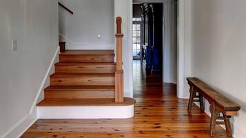 A wooden staircase leading to a landing with a bench and a chandelier.