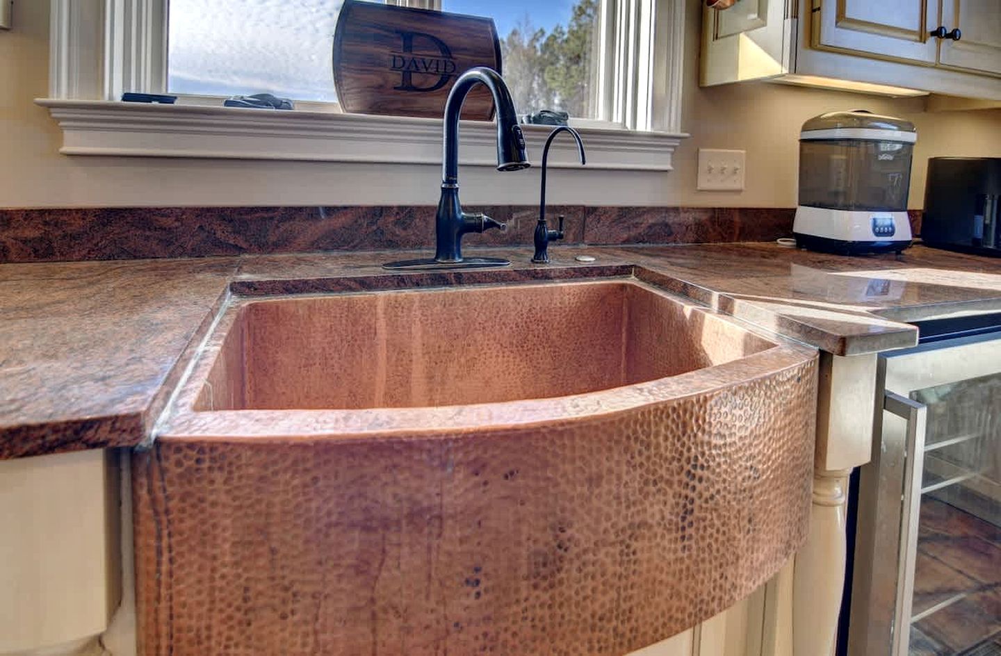 A kitchen with a granite countertop, a built-in sink, and a coffee maker.