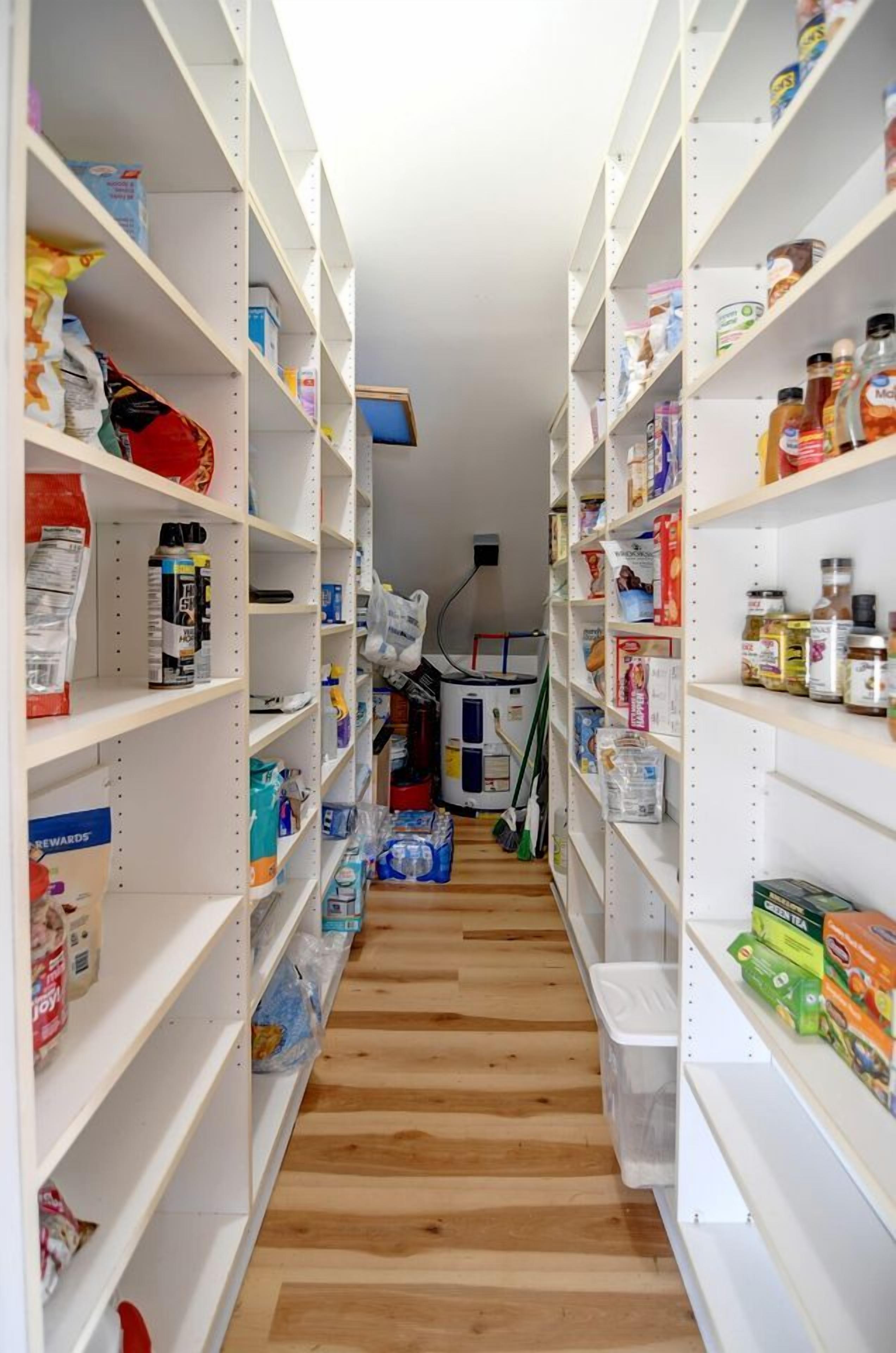 A narrow hallway with shelves stocked with various food items and household goods.