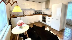 Eine moderne Küche mit weißen Schränken, einem schwarzen Kuhfellteppich und einem Esstisch mit einem Blumenarrangement.
