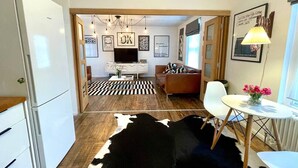 Eine moderne Küche mit Kühlschrank, ein Essbereich mit Tisch und Stühlen, eine Couch und ein Kuhfellteppich.