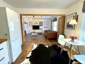 Eine moderne Küche mit Kühlschrank, ein Essbereich mit Tisch und Stühlen, eine Couch und ein Kuhfellteppich.