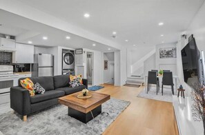 A modern living space with a kitchen, dining area, and a staircase leading to an upper level.