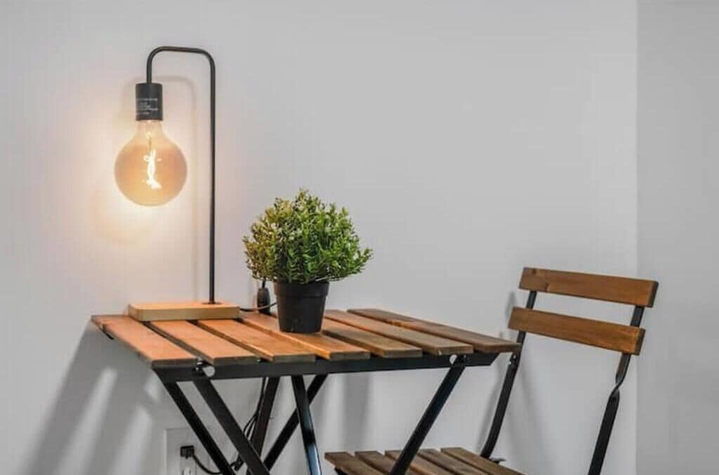 Une table avec une plante en pot et une ampoule suspendue.