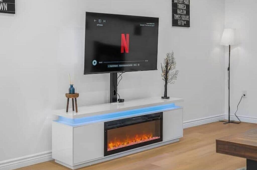 A modern living room with a flat-screen TV, a fireplace, and a minimalist design.