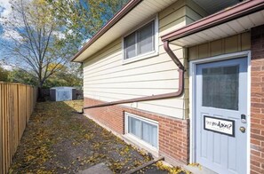 A two-story house with a front door, a small window, and a visible chimney. - Cozy Niagara Retreat with Fireplace (Thorold)