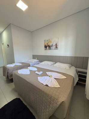 A hotel room with two beds, a headboard, a painting on the wall, and towels on the beds.