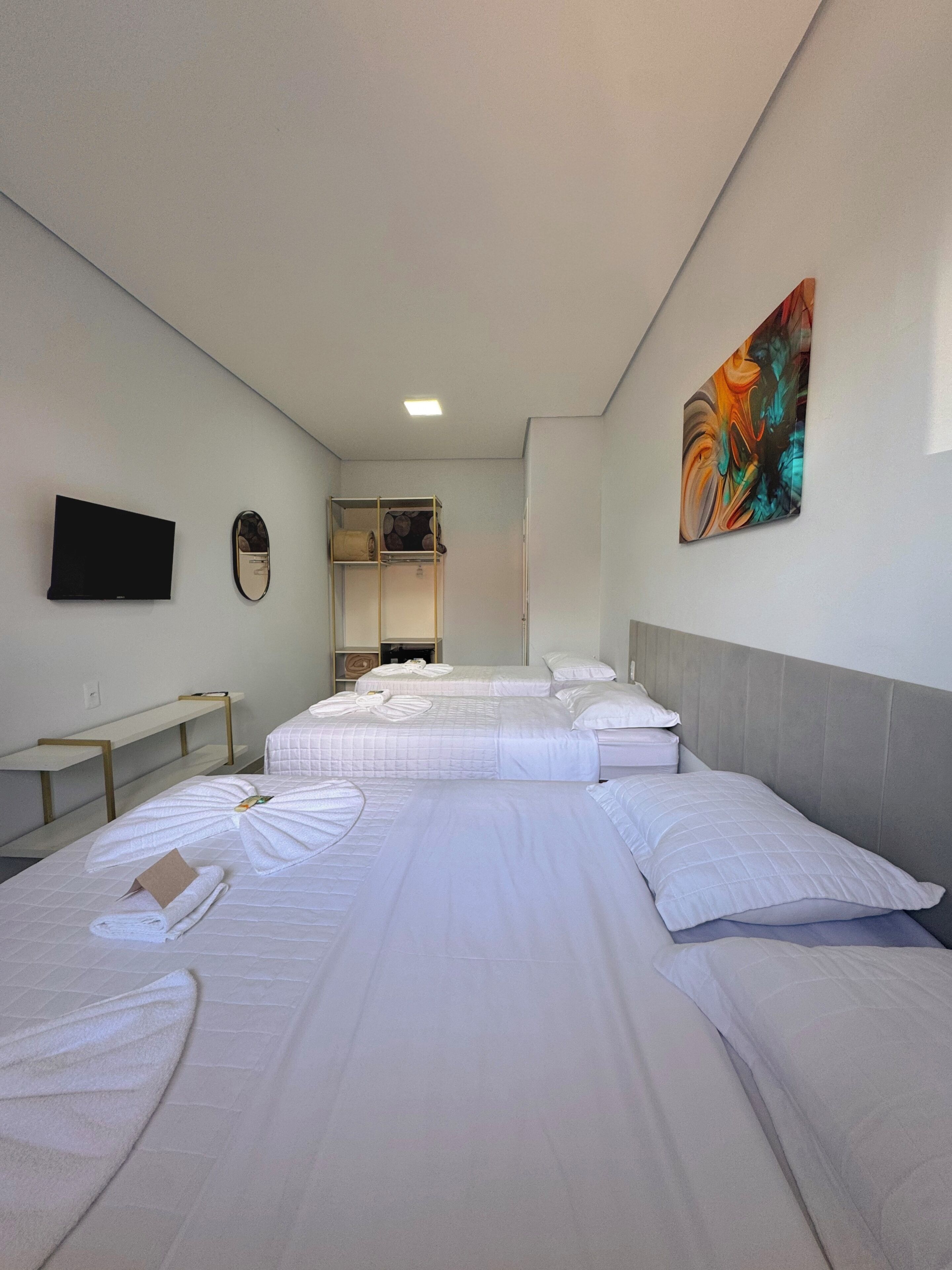 A hotel room with two beds, a flat-screen TV, a painting, and a small desk.