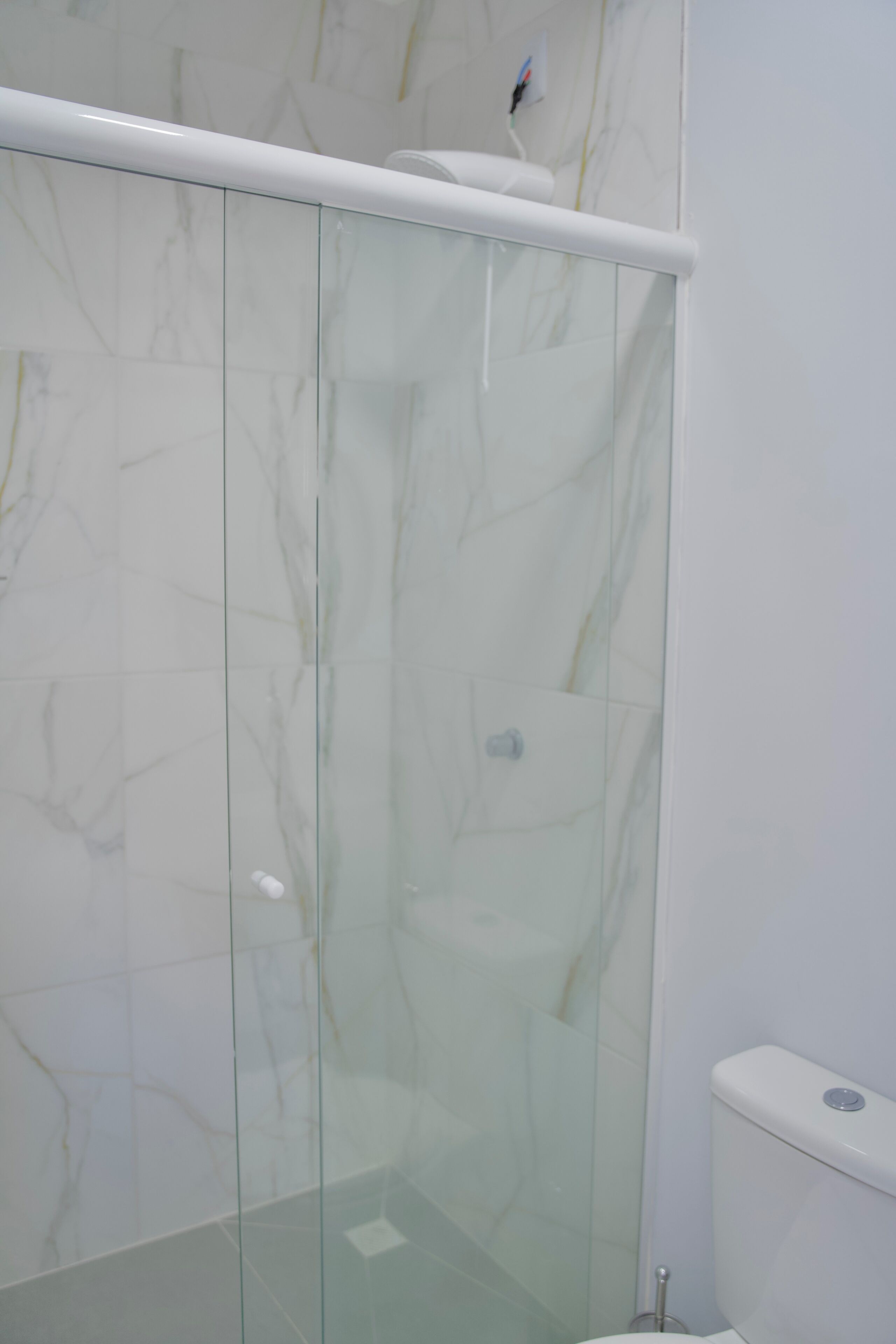 Cabina doccia vetrata con un water bianco visibile attraverso il vetro.