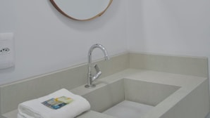 Un baño con un lavabo blanco, una toalla y un espejo redondo en la pared.