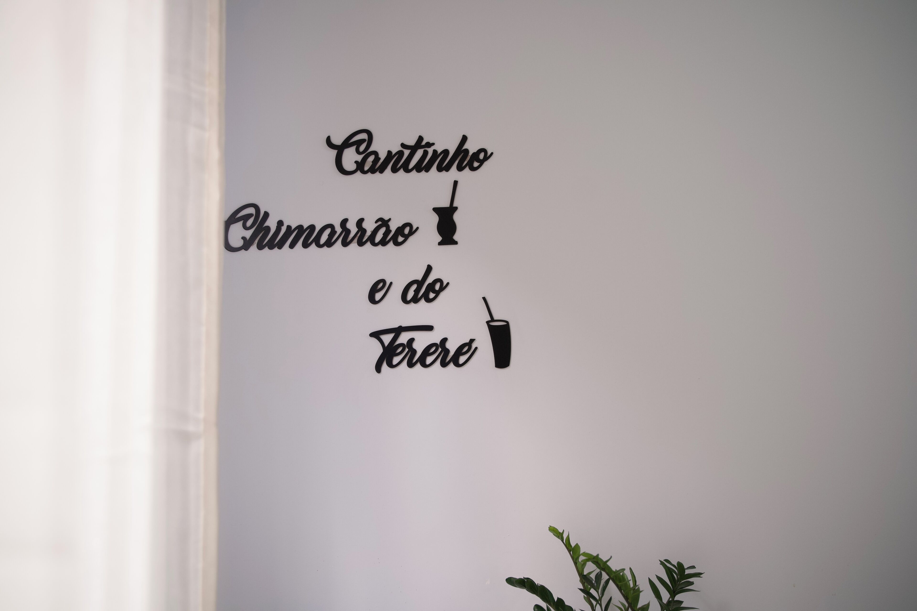 Un mur orné d’une enseigne décorative représentant une boisson et l’expression « Cantinho do Terê ».