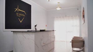 Una sala de estar moderna con una isla de mármol, una pared negra con un logotipo, una lámpara en el techo y una ventana con cortinas.