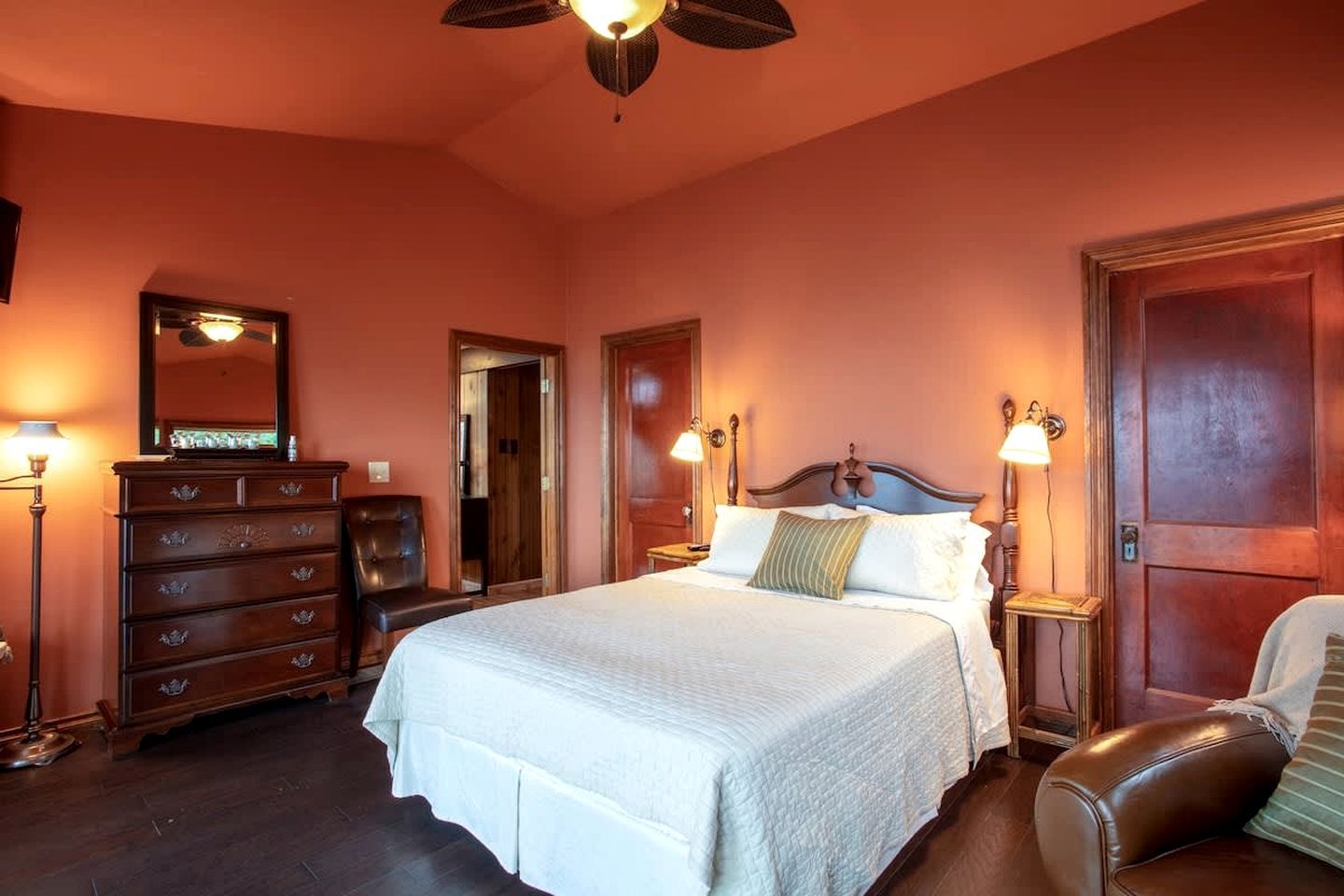 A bedroom with a large bed, wooden dresser, and two nightstands with lamps.