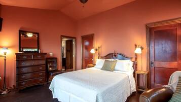 A bedroom with a large bed, wooden dresser, and two nightstands with lamps.