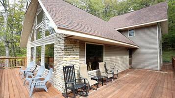 A two-story house with a deck, stone pillar, and outdoor seating area.