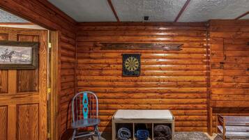 Una habitación con paredes de madera, un dardo, una silla y un banco con espacio de almacenamiento.