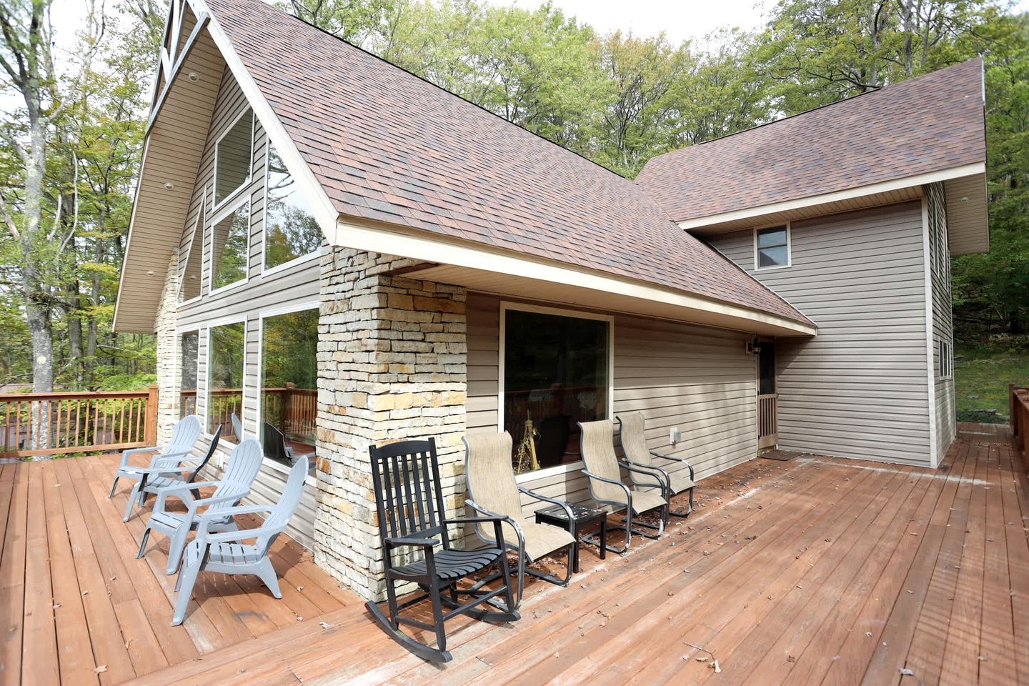 Een tweelaags huis met terras, stenen zuil en een zitgedeelte buiten.