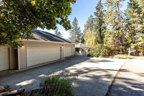 A two-story building with a garage, a covered porch, and a driveway leading to a street. - Enchanting Vacation Rental with Breathtaking Lake Views near Lake Fernan in Idaho (Coeur d'Alene)