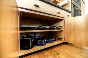 A wooden kitchen cabinet with multiple shelves, some containing cookware. - Enchanting Vacation Rental with Breathtaking Lake Views near Lake Fernan in Idaho (Coeur d'Alene)
