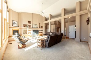 A spacious living room with a fireplace, a sofa, a television, and a dining area. - Enchanting Vacation Rental with Breathtaking Lake Views near Lake Fernan in Idaho (Coeur d'Alene)