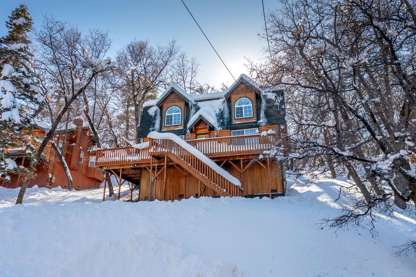 Una baita di legno con un balcone, circondata da alberi innevati.