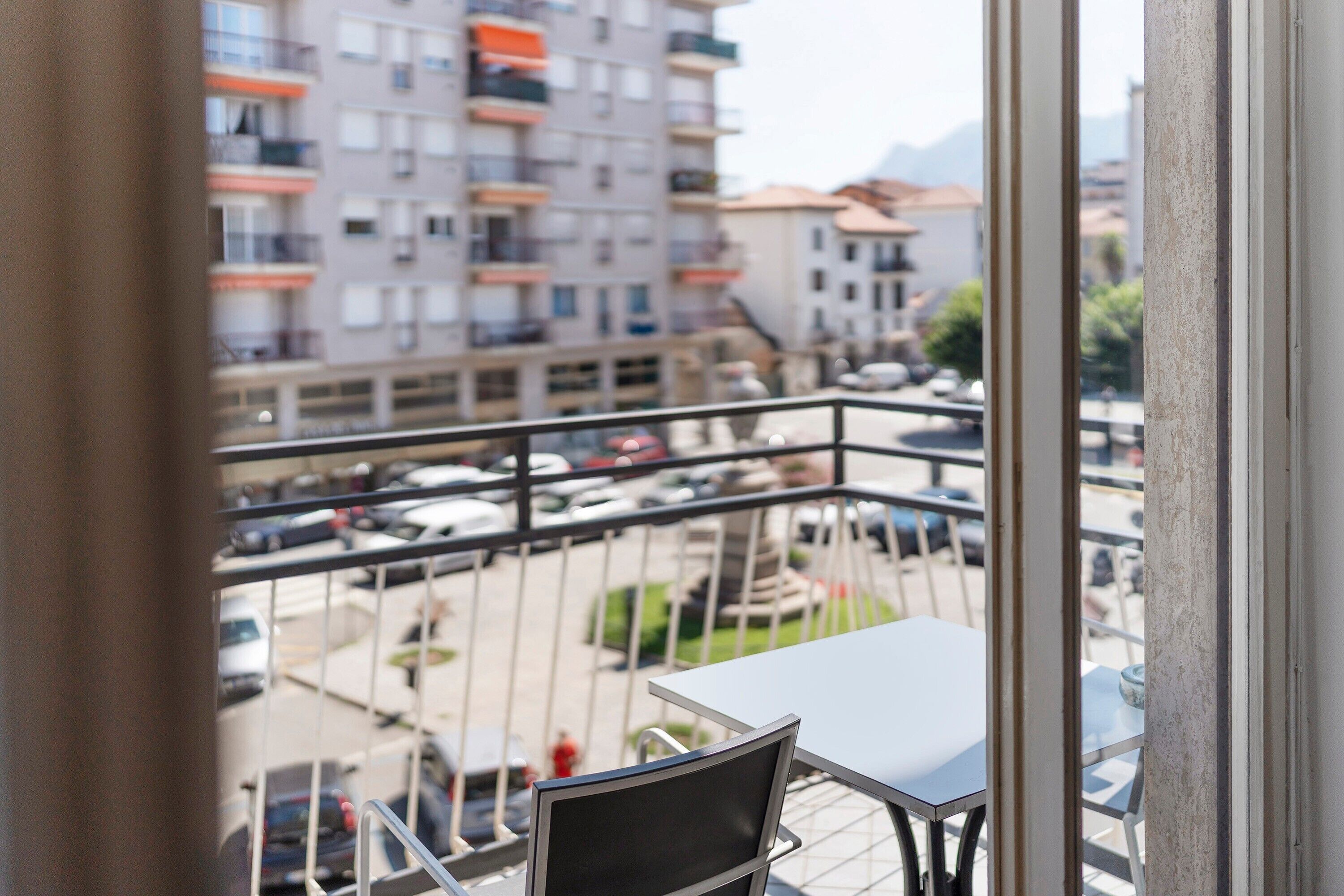 Ein Balkon mit Tisch und Stühlen, der auf einen Parkplatz und Gebäude blickt.