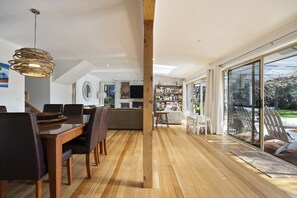 Ein großzügiger Wohnbereich mit Esstisch, Stühlen, Kamin und einer großen Bücherwand.