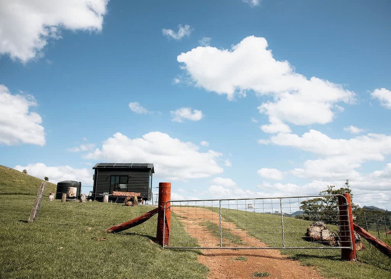 A rural setting with a fenced area, a building, and a clear sky.