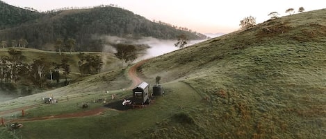 A rural landscape with a small building, a dirt path, and a body of water in the distance.