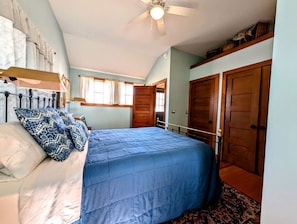 A bedroom with a bed, a ceiling fan, a window, and a door. - Picturesque Waterfront Cottage with Waterfall Views, Fireplace & Deck, Near Acadia National Park in Gouldsboro, Maine (Gouldsboro)