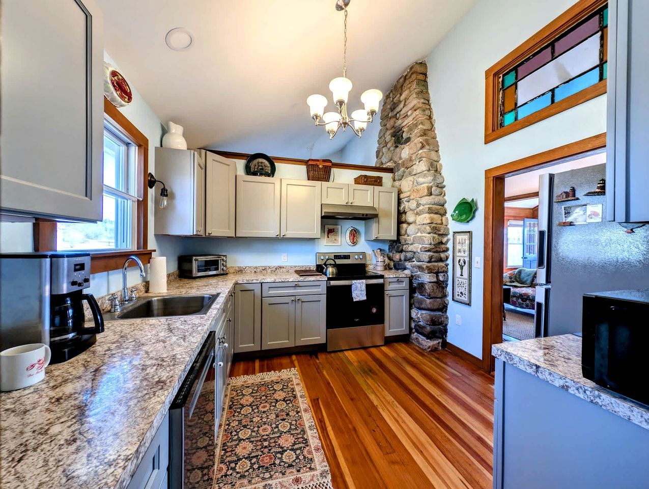 A kitchen with granite countertops, a stone wall, and a built-in oven.