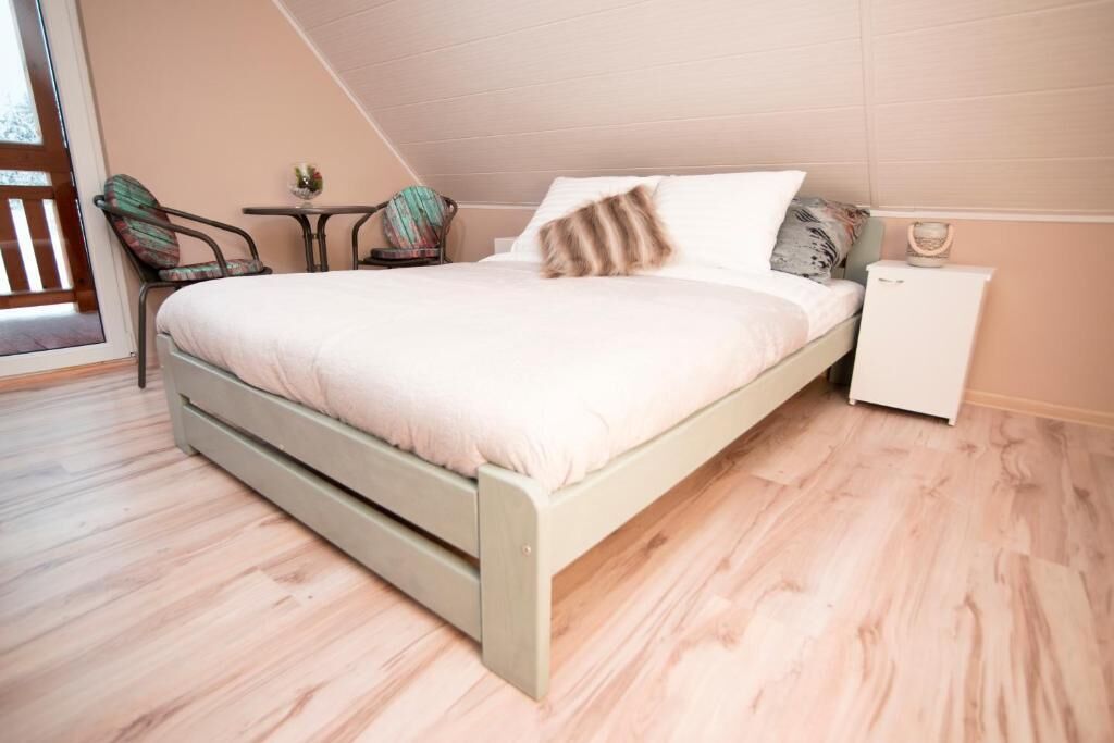 Una camera da letto con un letto, una sedia, un tavolino e un comodino.
