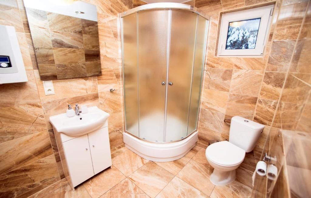 A bathroom with a shower enclosure, a sink, and a toilet.