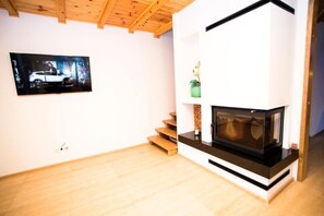 A modern living room with a fireplace, wooden flooring, and a mounted television.