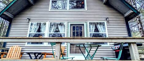 A cabin with a front porch, two windows, and a grill.