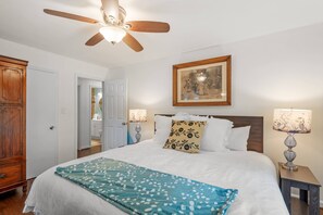 A bedroom with a bed, a ceiling fan, a painting, bedside lamps, and a wooden wardrobe. - New- Minutes from Atl Attractions, Hiking, Beltline, Backyard, Grill,  Pet Friendly (Atlanta)