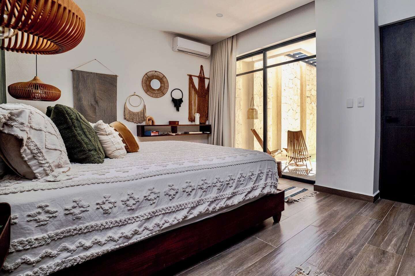 A bedroom with a large bed, a wooden floor, a window with a view, and a door.