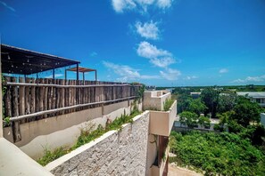 A rooftop terrace with a wooden pergola, a stone wall, and a view of a residential area. - Enjoy Tulum from Athara by HEUSHAVEN, a modern apartment in La Veleta, next to Central Park Lagunas. Ideal for couples or relaxed getaways, with a private pool, equipped kitchen, WiFi and amenities to unwind after the beach. (Tulum)