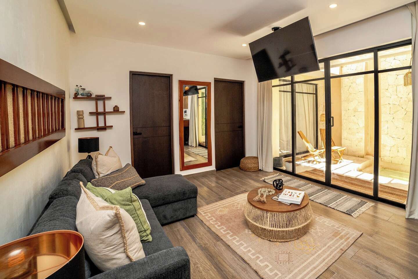 A modern living room with a sofa, a coffee table, and a large window with a view of an outdoor area.