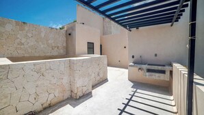 An outdoor patio with a stone wall, a built-in sink, and a pergola structure. - Enjoy Tulum from Athara by HEUSHAVEN, a modern apartment in La Veleta, next to Central Park Lagunas. Ideal for couples or relaxed getaways, with a private pool, equipped kitchen, WiFi and amenities to unwind after the beach. (Tulum)