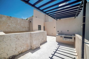Eine Terrasse im Freien mit einer Steinmauer, einem eingebauten Spülbecken und einer Pergola.