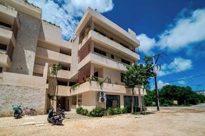 A multi-story building with balconies, a paved entrance, and parked scooters. - Enjoy Tulum from Athara by HEUSHAVEN, a modern apartment in La Veleta, next to Central Park Lagunas. Ideal for couples or relaxed getaways, with a private pool, equipped kitchen, WiFi and amenities to unwind after the beach. (Tulum)
