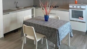 Una cocina moderna con armarios blancos, una mesa de comedor con mantel y una lámpara colgante.