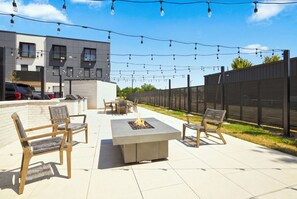An outdoor patio with a fire pit, seating, and string lights. - The Corridor - Garage - 0.5 mi DT (Bentonville)